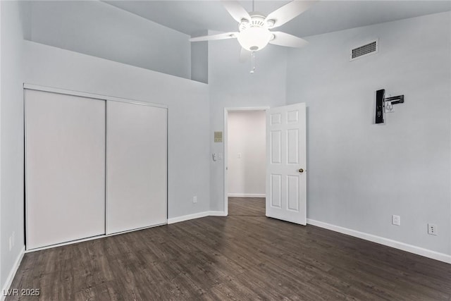 unfurnished bedroom with ceiling fan, dark hardwood / wood-style flooring, a closet, and high vaulted ceiling