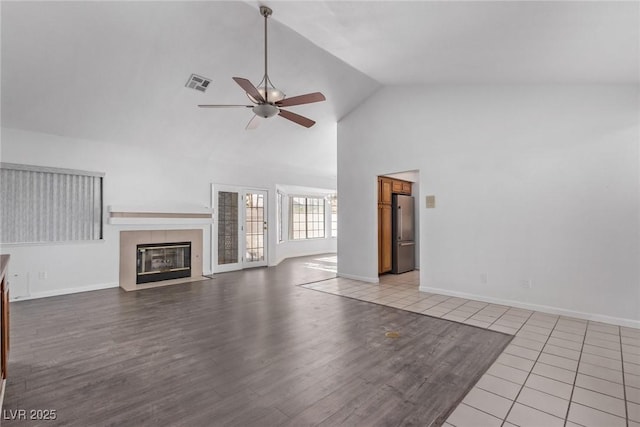 unfurnished living room featuring light tile patterned flooring, high vaulted ceiling, and ceiling fan