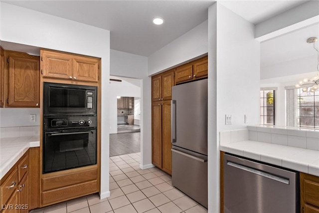 kitchen featuring black appliances, light tile patterned floors, a notable chandelier, and tile counters