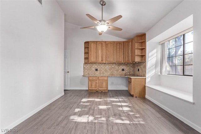 unfurnished office with ceiling fan, light hardwood / wood-style floors, lofted ceiling, and built in desk