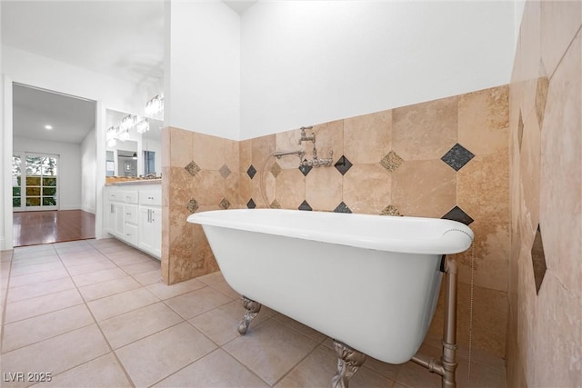 bathroom featuring a bathtub, tile patterned flooring, vanity, and tile walls