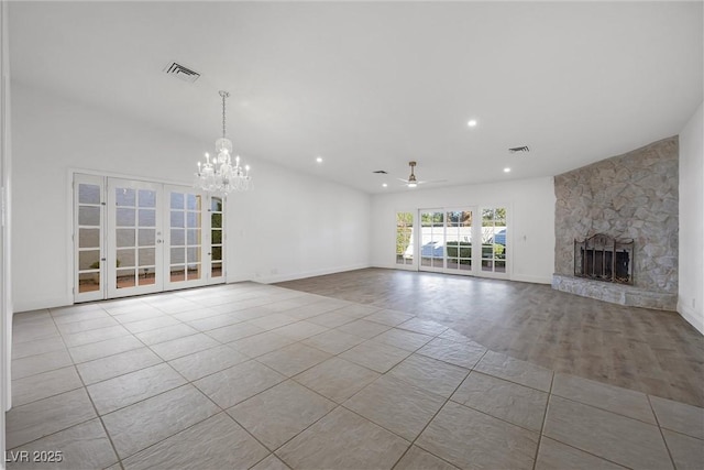 unfurnished living room featuring ceiling fan with notable chandelier, light tile patterned floors, french doors, and a fireplace