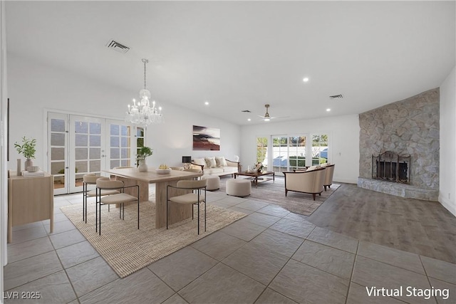 dining room featuring ceiling fan with notable chandelier, french doors, lofted ceiling, and a stone fireplace