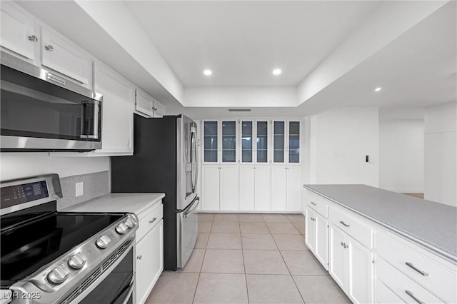 kitchen with backsplash, white cabinetry, light tile patterned floors, and stainless steel appliances