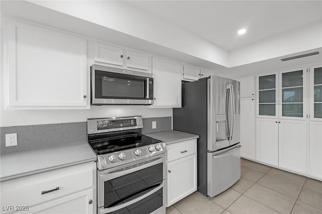 kitchen with white cabinets, light tile patterned floors, and stainless steel appliances