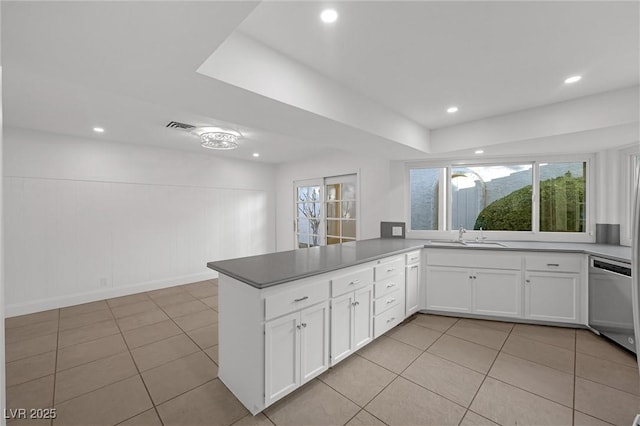 kitchen featuring white cabinets, kitchen peninsula, light tile patterned floors, and stainless steel dishwasher