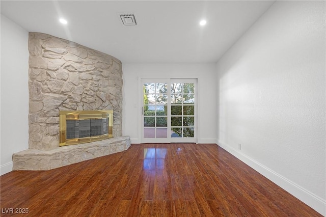 unfurnished living room with hardwood / wood-style floors and a stone fireplace