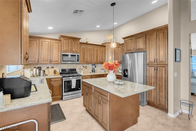 kitchen featuring pendant lighting, sink, a kitchen island, decorative backsplash, and stainless steel appliances