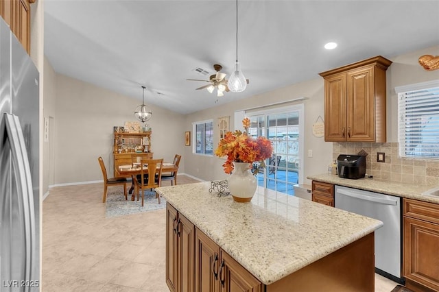 kitchen featuring a center island, stainless steel appliances, backsplash, hanging light fixtures, and vaulted ceiling