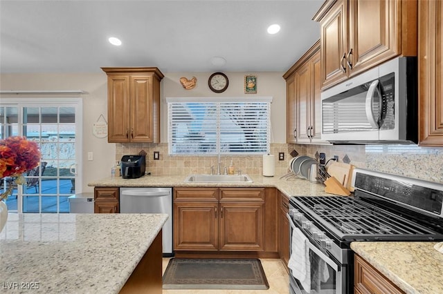 kitchen with sink, stainless steel appliances, a wealth of natural light, and light stone counters