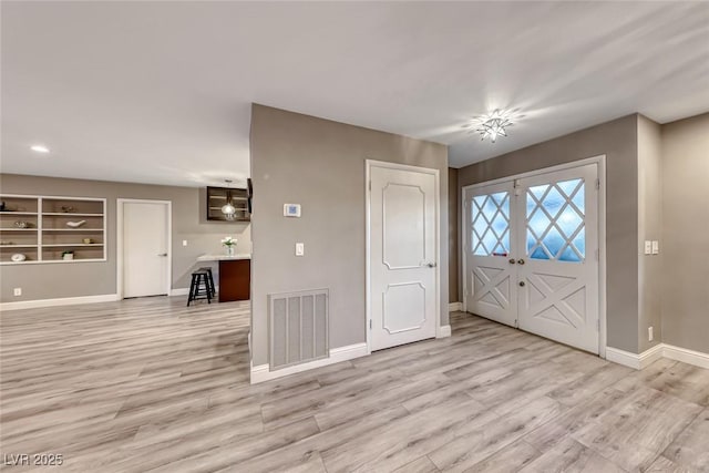 foyer entrance featuring french doors and light hardwood / wood-style flooring