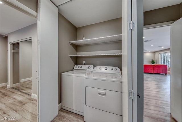 laundry room with washer and clothes dryer and light hardwood / wood-style flooring