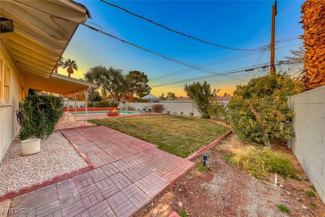 yard at dusk featuring a fenced in pool and a patio