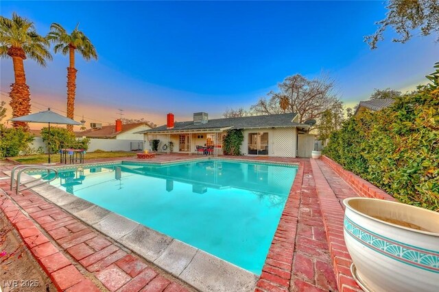 pool at dusk with a patio area