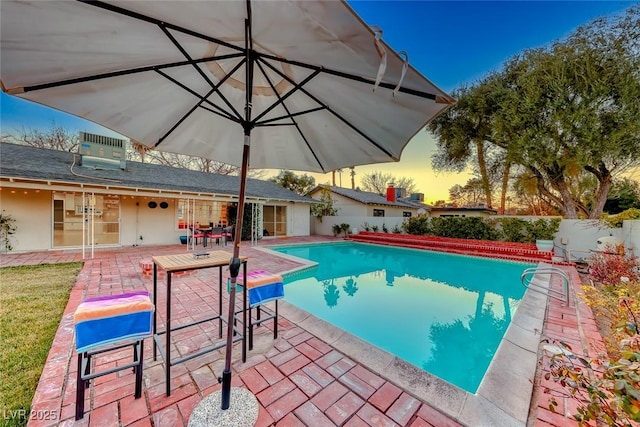 pool at dusk with central AC and a patio area