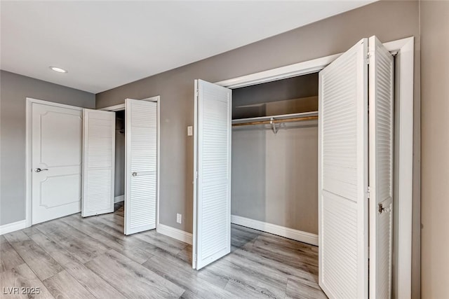 unfurnished bedroom featuring multiple closets and light hardwood / wood-style flooring