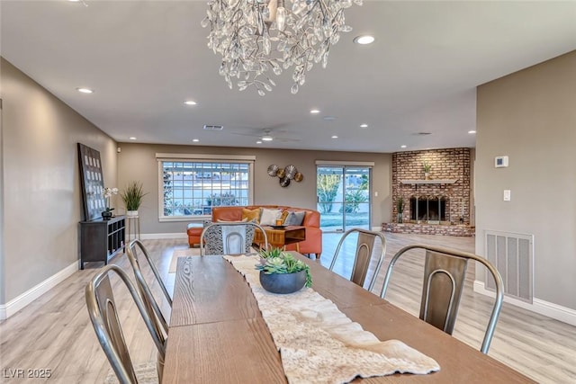 dining room featuring a brick fireplace, plenty of natural light, ceiling fan, and light hardwood / wood-style flooring