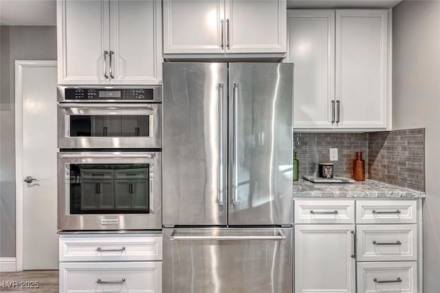 kitchen featuring stainless steel appliances, light stone countertops, and white cabinets