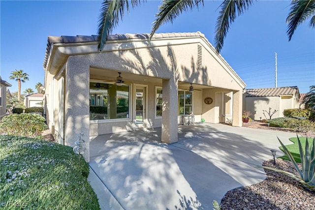 rear view of property featuring ceiling fan and a patio area