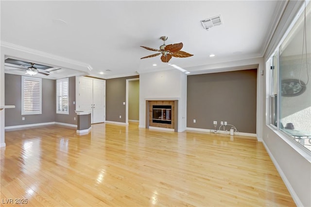 unfurnished living room featuring light wood-type flooring, ceiling fan, crown molding, and a fireplace