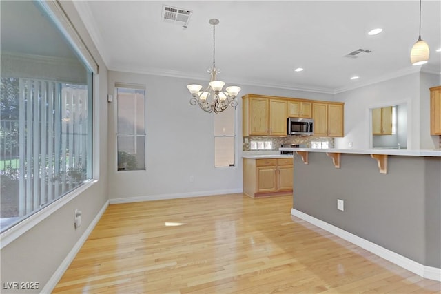 kitchen with pendant lighting, a kitchen bar, light hardwood / wood-style floors, light brown cabinetry, and ornamental molding