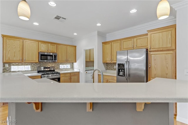 kitchen with crown molding, appliances with stainless steel finishes, decorative light fixtures, a breakfast bar, and decorative backsplash