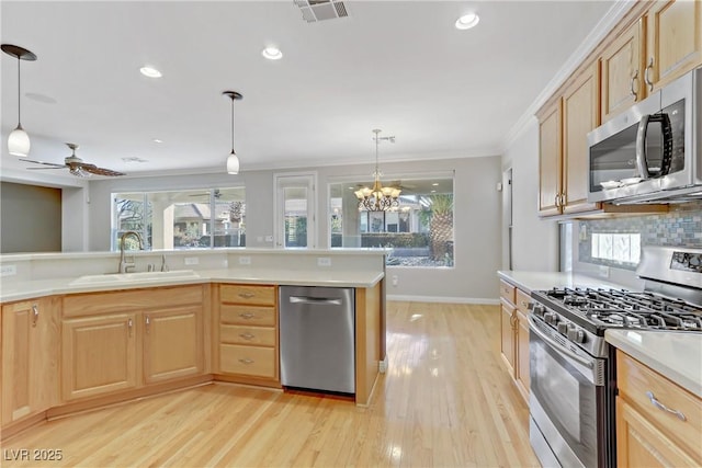 kitchen with sink, pendant lighting, light brown cabinetry, and appliances with stainless steel finishes