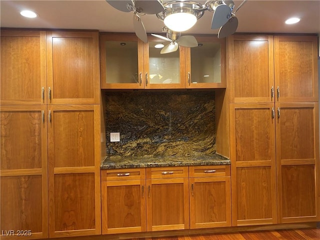 bar featuring decorative backsplash, hardwood / wood-style flooring, and dark stone counters