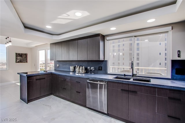 kitchen featuring dark brown cabinetry, sink, a tray ceiling, and stainless steel dishwasher