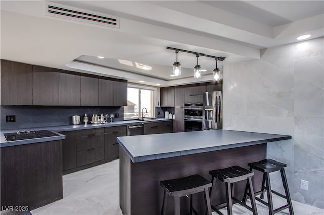 kitchen with backsplash, a kitchen breakfast bar, a raised ceiling, and appliances with stainless steel finishes