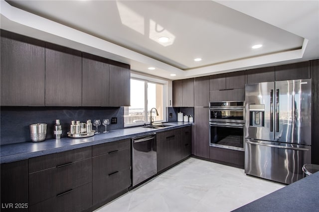 kitchen featuring appliances with stainless steel finishes, sink, dark brown cabinets, and a tray ceiling