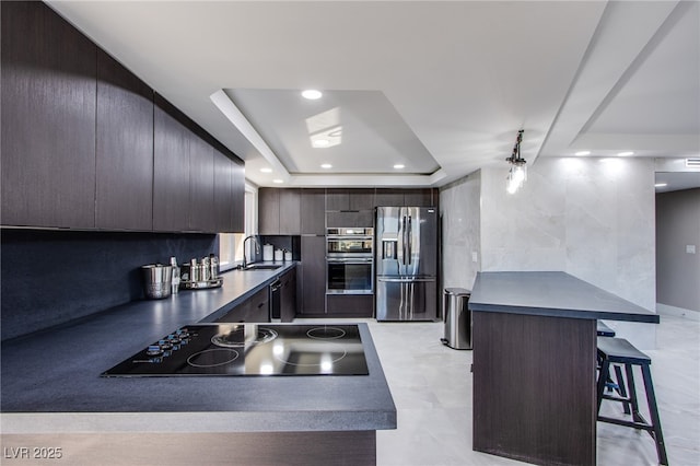 kitchen with dark brown cabinetry, sink, a breakfast bar area, and appliances with stainless steel finishes