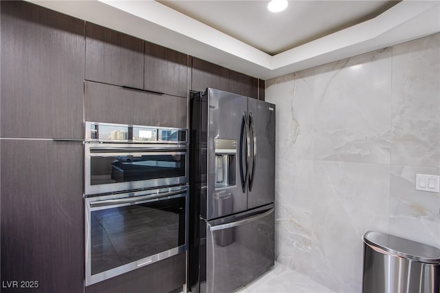 kitchen featuring appliances with stainless steel finishes, a tray ceiling, and tile walls