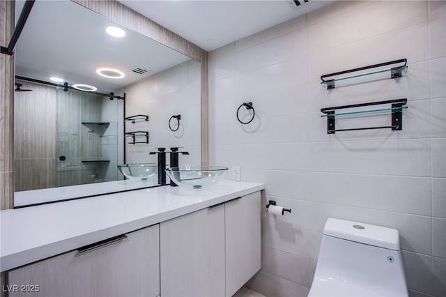 bathroom with vanity, toilet, and tile walls