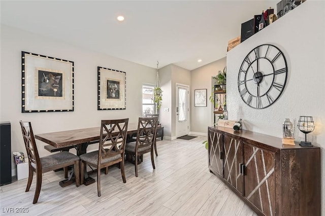 dining room featuring vaulted ceiling and light wood-type flooring