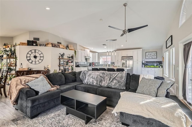 living room featuring vaulted ceiling, light hardwood / wood-style floors, and ceiling fan