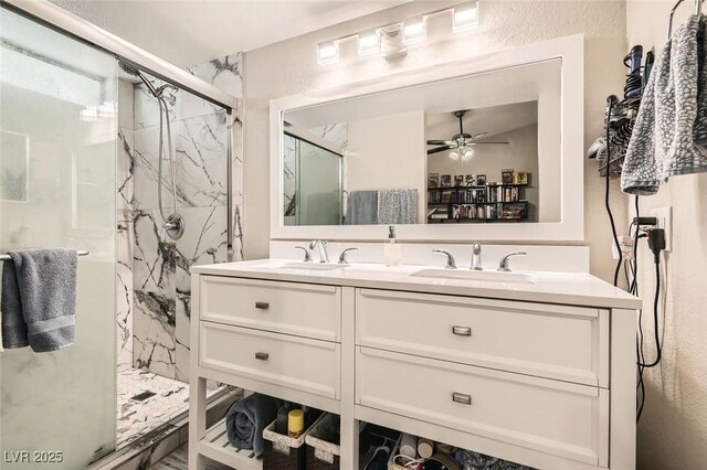 full bathroom featuring double vanity, a marble finish shower, a ceiling fan, and a sink