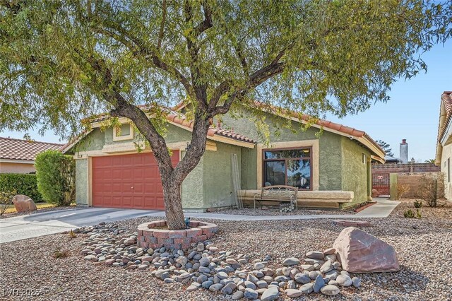 single story home featuring stucco siding, concrete driveway, an attached garage, fence, and a tiled roof