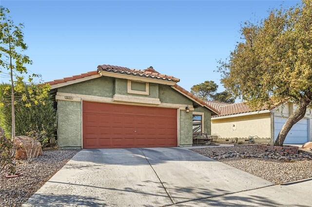 mediterranean / spanish home with a tile roof, driveway, an attached garage, and stucco siding