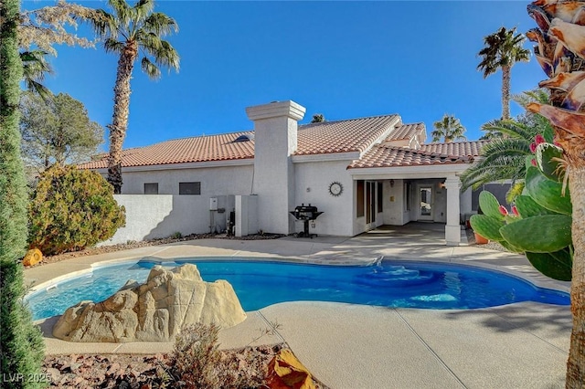 rear view of property with a fenced in pool and a patio