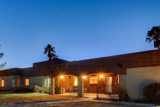 view of front of property featuring brick siding, a front yard, and a patio