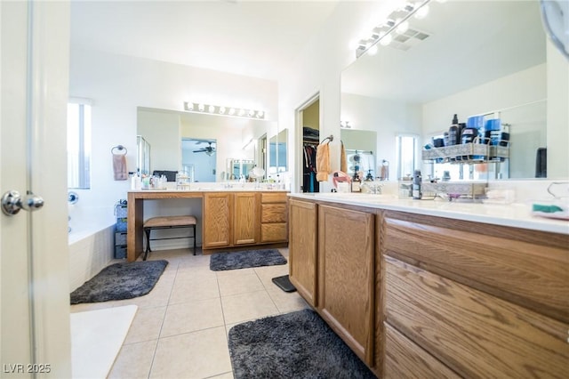 bathroom with ceiling fan, tile patterned floors, a relaxing tiled tub, and vanity