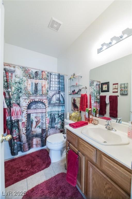 bathroom with toilet, vanity, and tile patterned flooring