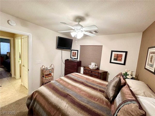 bedroom featuring ceiling fan, light tile patterned floors, and a textured ceiling