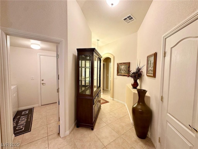 corridor with vaulted ceiling and light tile patterned flooring