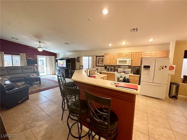 kitchen with lofted ceiling, backsplash, white appliances, light brown cabinets, and light tile patterned flooring