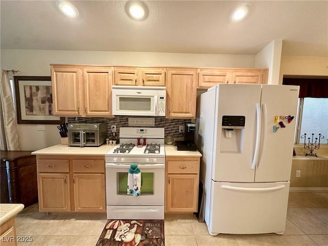 kitchen with white appliances, light brown cabinetry, and decorative backsplash