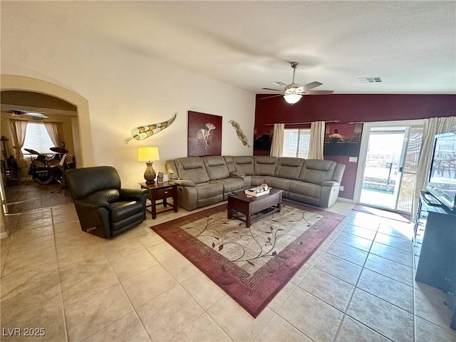 living room with a textured ceiling, vaulted ceiling, ceiling fan, and light tile patterned floors