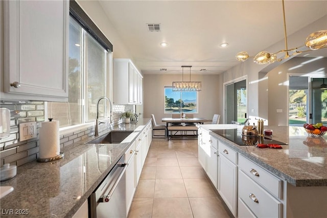 kitchen featuring sink, white cabinetry, hanging light fixtures, stone counters, and backsplash