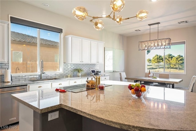 kitchen featuring sink, white cabinetry, stainless steel dishwasher, a kitchen island, and light stone countertops